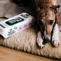 A pack of Beco Wipes Coconut, perfect for cleaning up your furry friend after a messy meal or adventure. With a happy dog lying nearby.